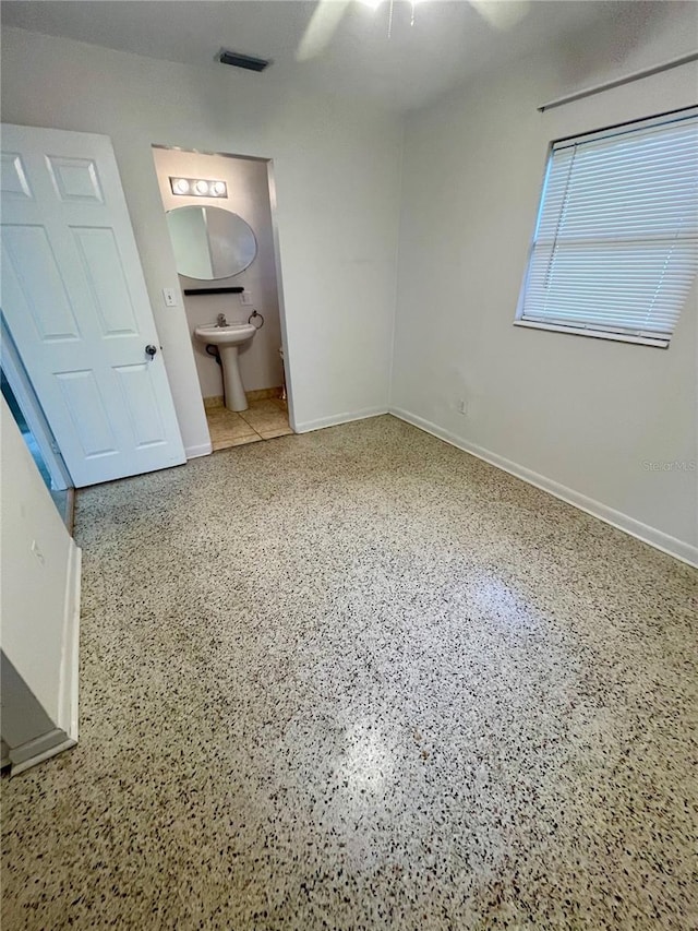 7026 20th St N, Saint Petersburg, FL 33702 - unfurnished bedroom featuring speckled floor, connected bathroom, and a ceiling fan