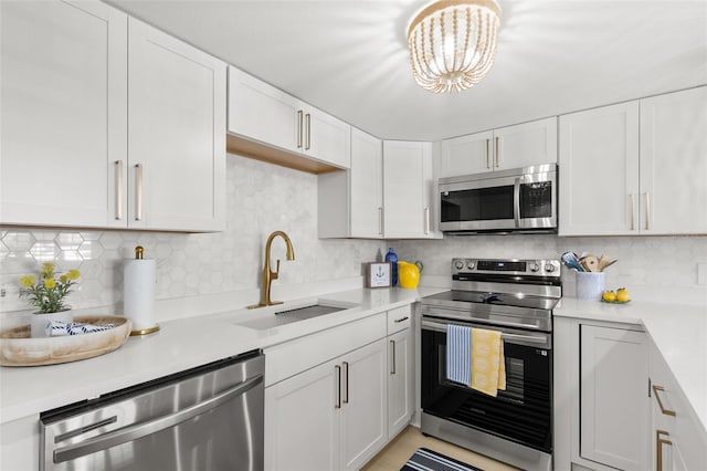 10280 Gulf Blvd Unit 12, Treasure Island, FL 33706 - kitchen with stainless steel appliances, light countertops, tasteful backsplash, white cabinets, and a chandelier