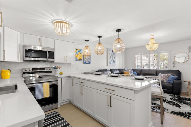 10280 Gulf Blvd Unit 12, Treasure Island, FL 33706 - kitchen featuring stainless steel appliances, open floor plan, a peninsula, and a chandelier