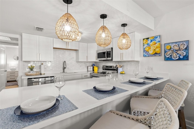 10280 Gulf Blvd Unit 12, Treasure Island, FL 33706 - kitchen with stainless steel appliances, backsplash, a breakfast bar, and white cabinetry
