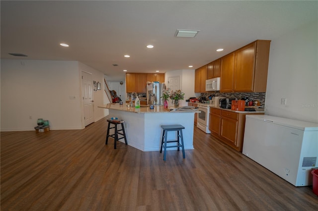 1708 Abbey Trace Dr, Dover, FL 33527 - kitchen with white appliances, a breakfast bar, recessed lighting, dark wood finished floors, and brown cabinets