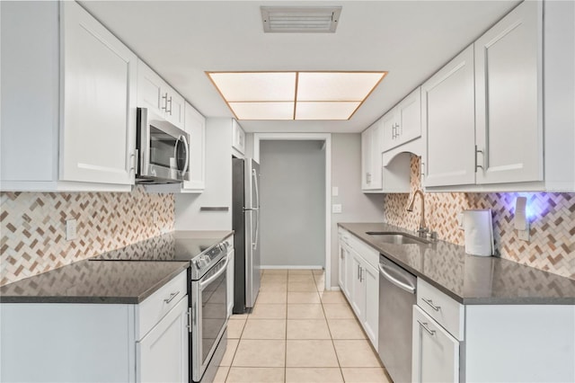 7108 14th Ave NW, Bradenton, FL 34209 - kitchen featuring stainless steel appliances, dark countertops, light tile patterned flooring, and white cabinetry