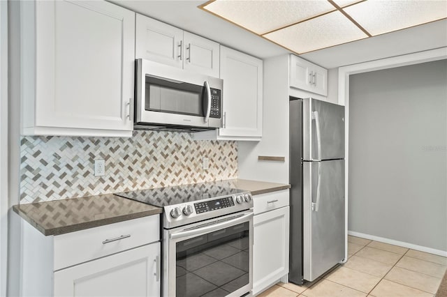 7108 14th Ave NW, Bradenton, FL 34209 - kitchen featuring appliances with stainless steel finishes, dark countertops, white cabinets, light tile patterned floors, and backsplash
