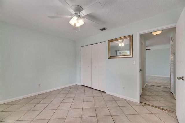 1049 Apollo Beach Blvd Unit D, Apollo Beach, FL 33572 - unfurnished bedroom with light tile patterned floors, a closet, a textured ceiling, and a ceiling fan