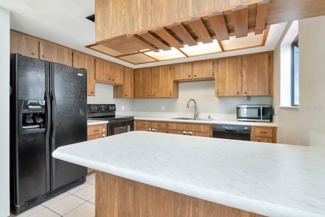 9501 Alice Ln, Riverview, FL 33578 - kitchen with black appliances, light tile patterned floors, light countertops, a peninsula, and brown cabinetry
