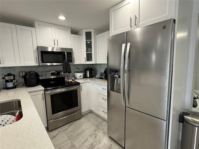 2927 W Henry Ave, Tampa, FL 33614 - kitchen featuring appliances with stainless steel finishes, white cabinets, backsplash, glass insert cabinets, and recessed lighting