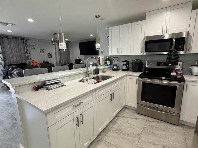 2927 W Henry Ave, Tampa, FL 33614 - kitchen featuring appliances with stainless steel finishes, a peninsula, backsplash, white cabinetry, and recessed lighting