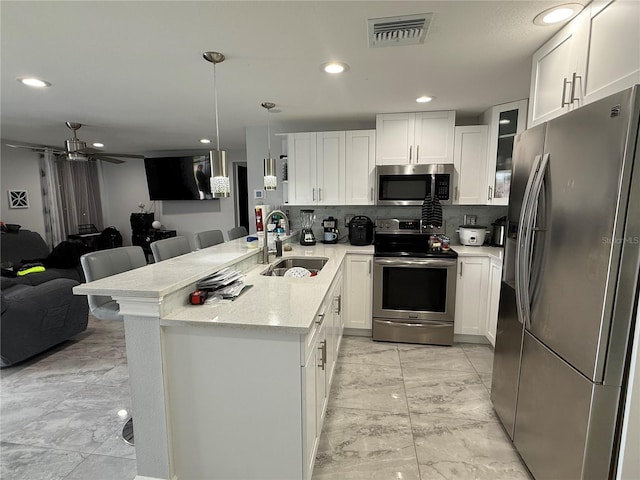 2927 W Henry Ave, Tampa, FL 33614 - kitchen with appliances with stainless steel finishes, open floor plan, decorative backsplash, white cabinetry, and recessed lighting