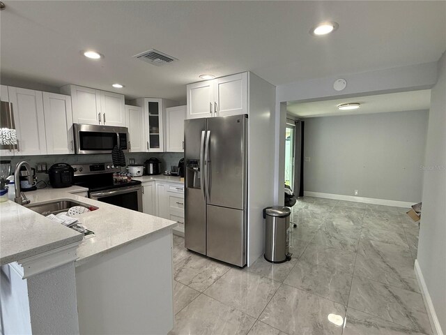 2927 W Henry Ave, Tampa, FL 33614 - kitchen with stainless steel appliances, white cabinets, backsplash, a peninsula, and glass insert cabinets