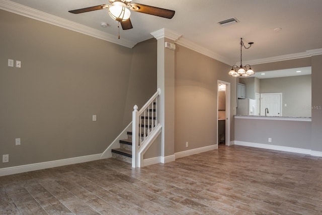 3298 Covered Bridge Dr W, Dunedin, FL 34698 - unfurnished living room with a ceiling fan, crown molding, wood finished floors, stairway, and a chandelier