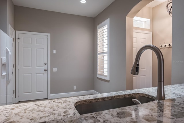 3298 Covered Bridge Dr W, Dunedin, FL 34698 - kitchen featuring arched walkways, light stone counters, white fridge with ice dispenser, and recessed lighting