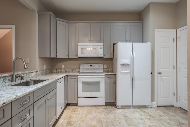 3298 Covered Bridge Dr W, Dunedin, FL 34698 - kitchen with white appliances, gray cabinets, light stone countertops, and light wood-style flooring