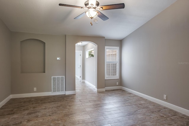 3298 Covered Bridge Dr W, Dunedin, FL 34698 - unfurnished room featuring arched walkways, wood finished floors, ceiling fan, and vaulted ceiling