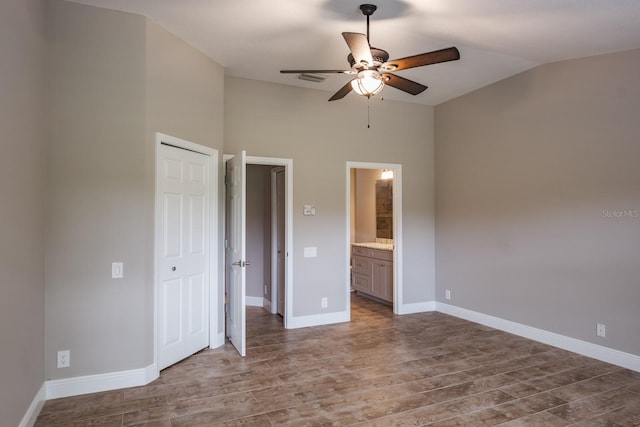 3298 Covered Bridge Dr W, Dunedin, FL 34698 - unfurnished bedroom featuring wood finished floors, vaulted ceiling, a closet, ensuite bathroom, and ceiling fan