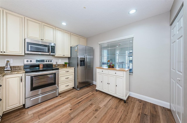 5157 Silent Loop Unit 301, New Port Richey, FL 34652 - kitchen with appliances with stainless steel finishes, cream cabinetry, light wood-type flooring, recessed lighting, and a textured ceiling
