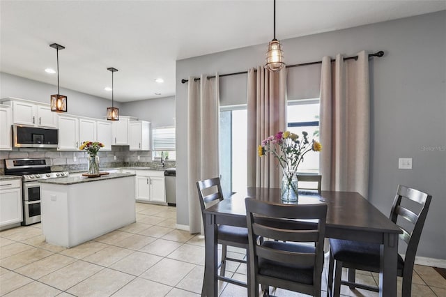 1811 Palm Warbler Ln, Ruskin, FL 33570 - kitchen featuring stainless steel appliances, decorative backsplash, white cabinets, light tile patterned flooring, and hanging light fixtures