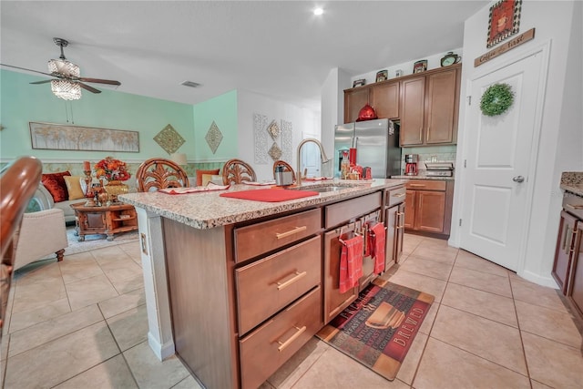 289 Siesta Vista Ct, Davenport, FL 33896 - kitchen featuring freestanding refrigerator, ceiling fan, light tile patterned flooring, a center island with sink, and light stone countertops