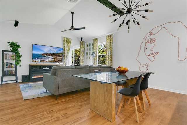 356 Irving Bend Dr, Groveland, FL 34736 - dining room featuring light wood-type flooring, vaulted ceiling, a glass covered fireplace, a chandelier, and ceiling fan