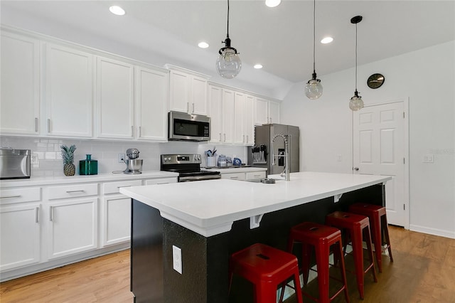 356 Irving Bend Dr, Groveland, FL 34736 - kitchen featuring appliances with stainless steel finishes, an island with sink, light wood-type flooring, white cabinetry, and recessed lighting