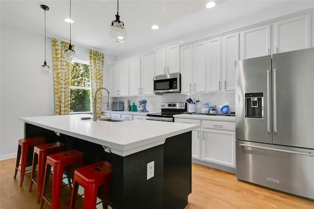 356 Irving Bend Dr, Groveland, FL 34736 - kitchen featuring appliances with stainless steel finishes, a kitchen island with sink, white cabinets, light countertops, and light wood-type flooring
