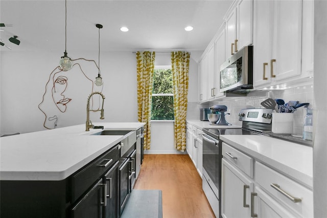 356 Irving Bend Dr, Groveland, FL 34736 - kitchen with appliances with stainless steel finishes, dark cabinetry, light countertops, light wood-style flooring, and recessed lighting