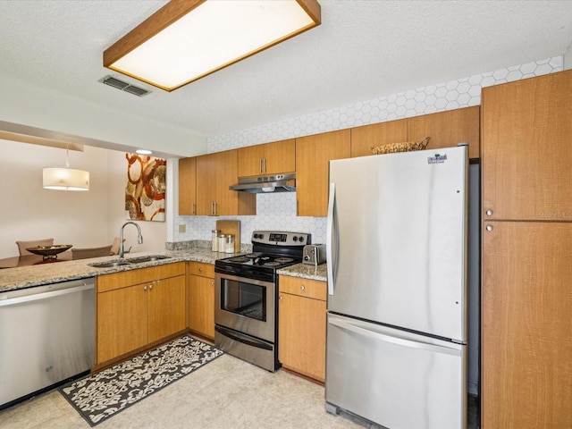 4220 Revere Cir, New Port Richey, FL 34653 - kitchen with stainless steel appliances, under cabinet range hood, brown cabinetry, light stone countertops, and backsplash