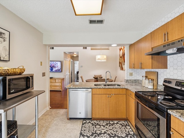 4220 Revere Cir, New Port Richey, FL 34653 - kitchen featuring appliances with stainless steel finishes, under cabinet range hood, a peninsula, backsplash, and brown cabinets