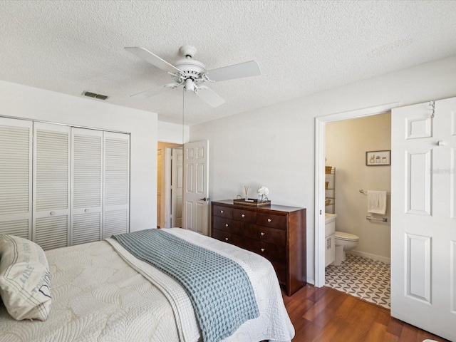4220 Revere Cir, New Port Richey, FL 34653 - bedroom featuring a closet, dark wood-type flooring, a textured ceiling, connected bathroom, and a ceiling fan