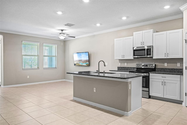 31945 Blue Passing Loop, Wesley Chapel, FL 33545 - kitchen with stainless steel appliances, ornamental molding, a kitchen island with sink, dark stone countertops, and a ceiling fan