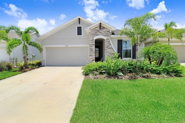 11809 Catawba Cv, Parrish, FL 34219 - view of front of property with a garage, a front yard, driveway, stucco siding, and stone siding