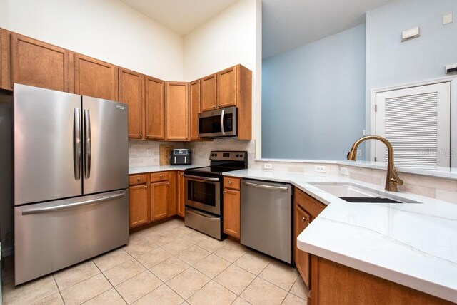 7001 Interbay Blvd Unit 121, Tampa, FL 33616 - kitchen with stainless steel appliances, brown cabinetry, backsplash, light tile patterned floors, and a peninsula