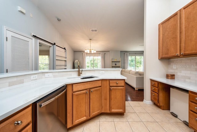 7001 Interbay Blvd Unit 121, Tampa, FL 33616 - kitchen with dishwasher, backsplash, open floor plan, brown cabinets, and light tile patterned floors