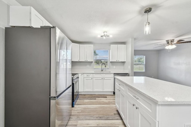 38323 11th Ave, Zephyrhills, FL 33542 - kitchen with stainless steel appliances, white cabinets, light wood-style flooring, ceiling fan, and light stone counters