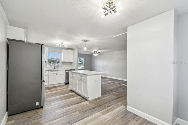 38323 11th Ave, Zephyrhills, FL 33542 - kitchen featuring appliances with stainless steel finishes, white cabinets, light countertops, a kitchen island, and light wood-style flooring