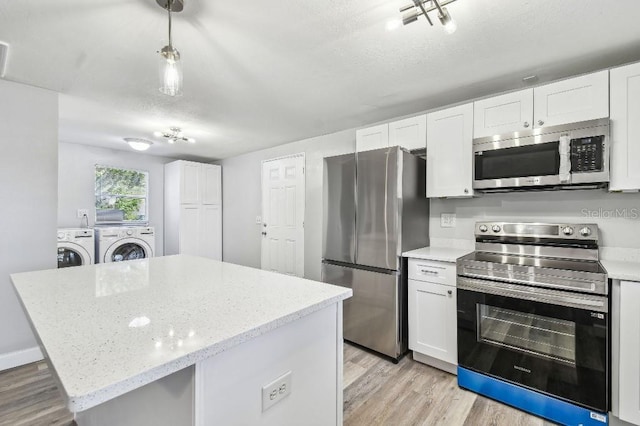 38323 11th Ave, Zephyrhills, FL 33542 - kitchen with appliances with stainless steel finishes, washing machine and clothes dryer, light wood-style flooring, white cabinetry, and a kitchen island