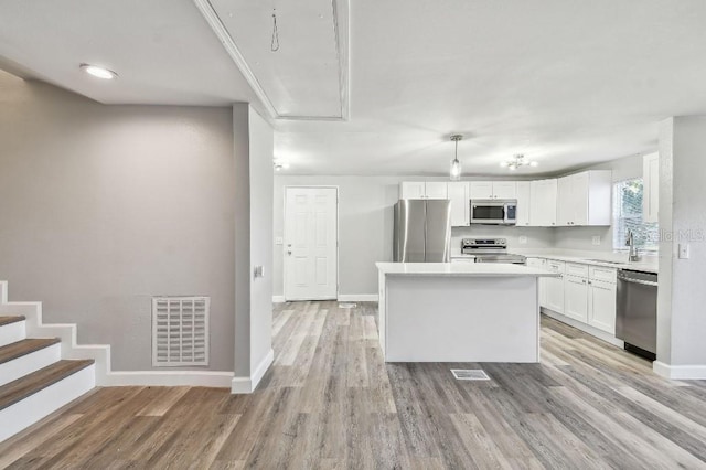 38323 11th Ave, Zephyrhills, FL 33542 - kitchen featuring stainless steel appliances, white cabinetry, a center island, light countertops, and light wood-style floors