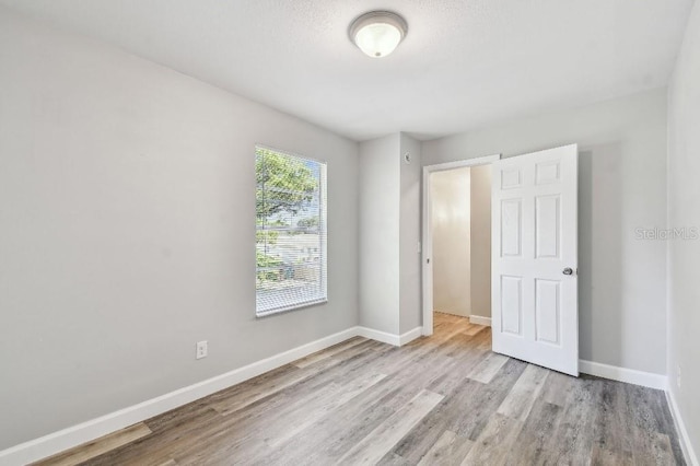38323 11th Ave, Zephyrhills, FL 33542 - unfurnished bedroom featuring wood finished floors and baseboards