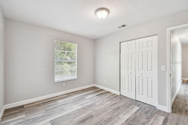 38323 11th Ave, Zephyrhills, FL 33542 - unfurnished bedroom with wood finished floors, a closet, and a textured ceiling