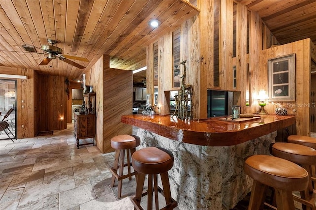 935 Ranch Rd, Tarpon Springs, FL 34688 - indoor dry bar featuring wood walls, stone tile flooring, wood ceiling, a ceiling fan, and black fridge