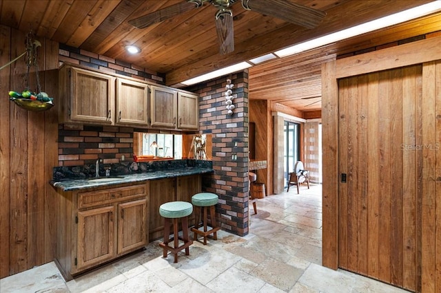 935 Ranch Rd, Tarpon Springs, FL 34688 - kitchen featuring stone tile floors, ceiling fan, dark countertops, wood walls, and wood ceiling