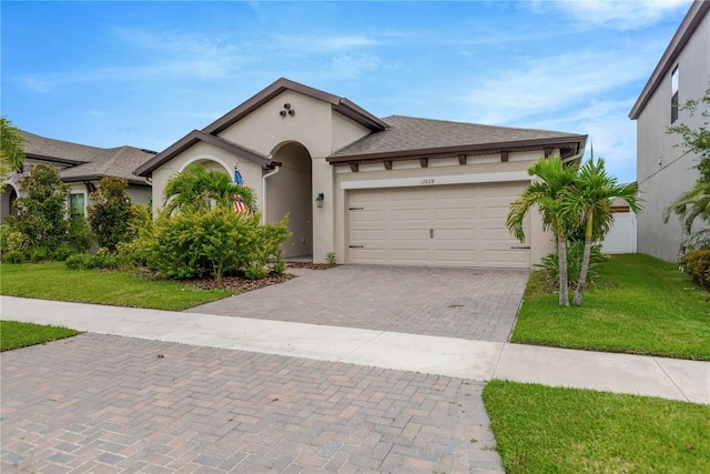 12828 Satin Lily Dr, Riverview, FL 33579 - mediterranean / spanish house featuring stucco siding, a front yard, decorative driveway, and an attached garage
