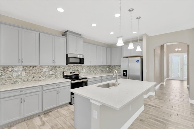 12828 Satin Lily Dr, Riverview, FL 33579 - kitchen with stainless steel appliances, arched walkways, backsplash, an island with sink, and light countertops