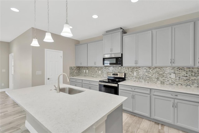 12828 Satin Lily Dr, Riverview, FL 33579 - kitchen with appliances with stainless steel finishes, gray cabinetry, decorative backsplash, a center island with sink, and light countertops