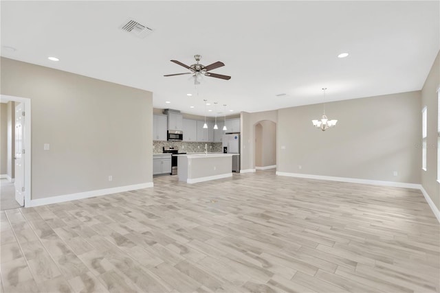 12828 Satin Lily Dr, Riverview, FL 33579 - unfurnished living room featuring ceiling fan, a chandelier, arched walkways, light wood-type flooring, and recessed lighting