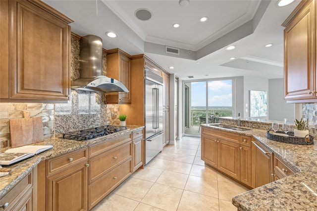 400 Beach Dr NE Unit 2301, Saint Petersburg, FL 33701 - kitchen with wall chimney range hood, appliances with stainless steel finishes, tasteful backsplash, light stone counters, and brown cabinetry