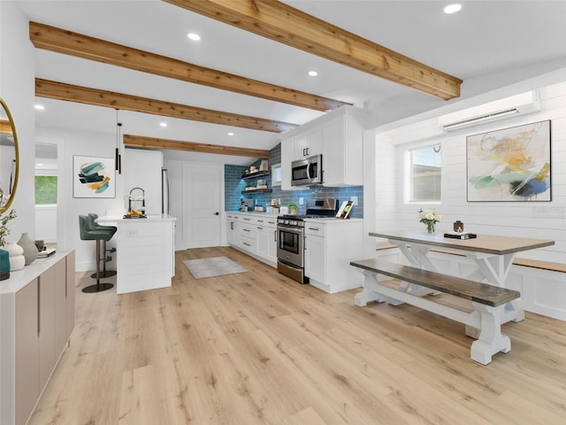960 65th St S, Saint Petersburg, FL 33707 - kitchen featuring appliances with stainless steel finishes, white cabinets, recessed lighting, light countertops, and a wall unit AC