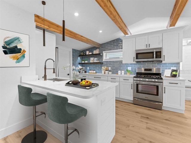 960 65th St S, Saint Petersburg, FL 33707 - kitchen featuring stainless steel appliances, light wood-style floors, backsplash, a kitchen breakfast bar, and recessed lighting