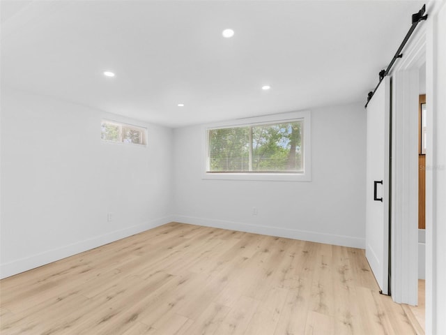 960 65th St S, Saint Petersburg, FL 33707 - unfurnished bedroom featuring a barn door, light wood-style flooring, and recessed lighting
