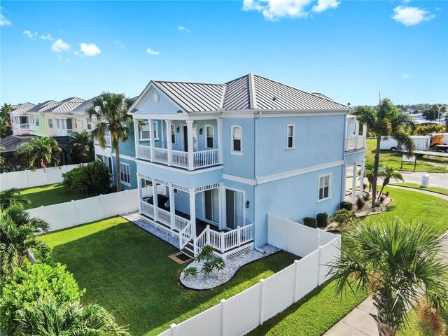 6545 Simone Shores Cir, Apollo Beach, FL 33572 - rear view of property with a balcony, a standing seam roof, a fenced backyard, stucco siding, and covered porch