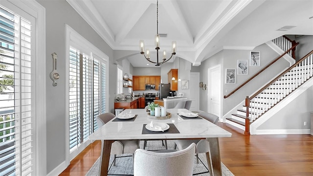 6545 Simone Shores Cir, Apollo Beach, FL 33572 - dining space with wood finished floors, a chandelier, ornamental molding, stairway, and lofted ceiling